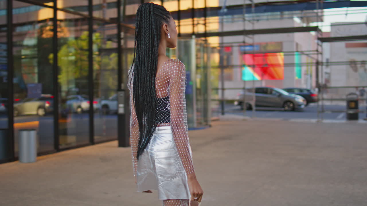 Donna alla moda che percorre una scalinata al tramonto in città. Brunetta elegante che cammina.