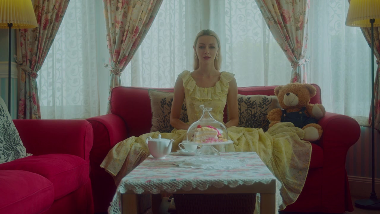 Young Woman Sitting on Red Sofa with Teddy Bear and Cake