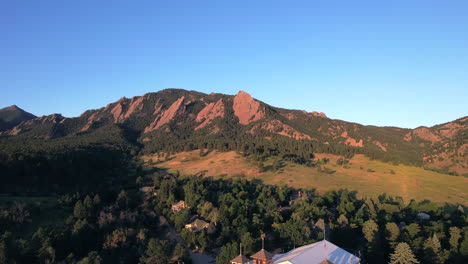 drone rising up in chautauqua park revealing the flatirons nature area and houses during sunrise on a summer morning