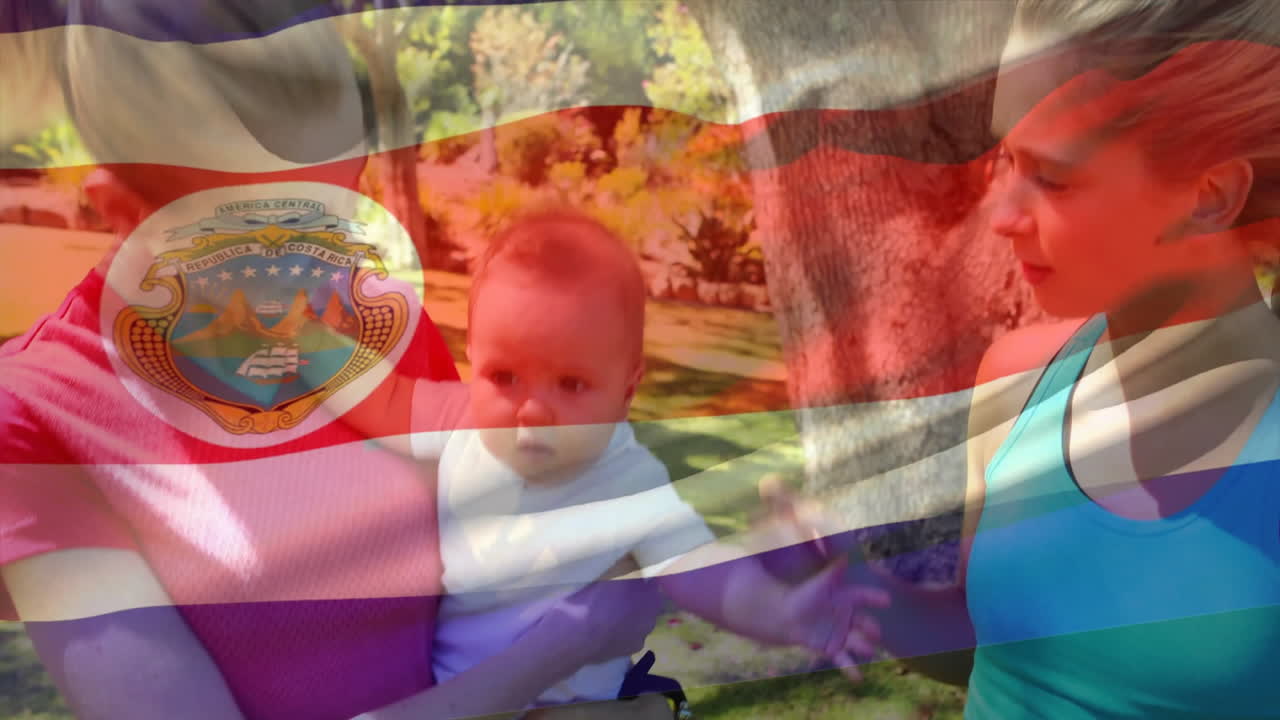 Holding baby with Costa Rican flag overlay, two women standing in park