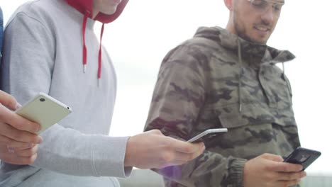 close up of friends holding modern mobile phone in hands