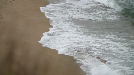 Seitenansicht-Von-Wellen,-Die-Den-Sand-Vertiefen,-Aufgenommen-In-Zeitlupe-Mit-Teleobjektiv-Von-Einem-Höheren-Standpunkt-Aus