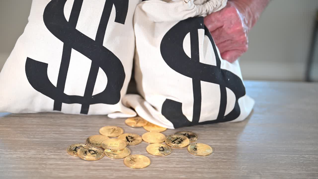 두 봉투의 현금과 함께 반이는 밝은 금색 토큰 비트코인 노인 노동자의 손에 붙어 있습니다.