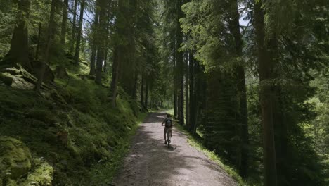 Aerial-tracking-shot-of-cyclist-on-sport-bike-riding-on-rocky-path-in-mountains-during-summer