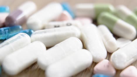 assorted pills and capsules scattered on a wooden surface in close-up view