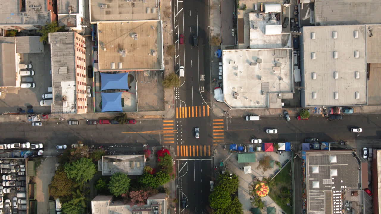 Aerial view of an urban landscape featuring a street intersection, commercial buildings, and a public park with recreational facilities