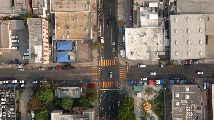 Aerial view of an urban landscape featuring a street intersection, commercial buildings, and a public park with recreational facilities