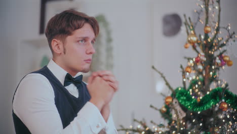 depressed man at home with christmas tree in background