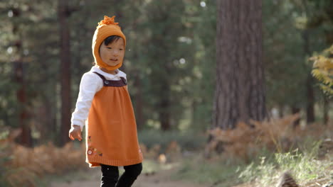 asian toddler girl plays with pine cone in a forest, close up