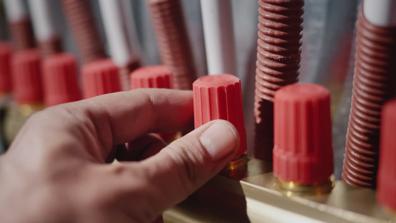 A man's hand adjusts the heat supply to the comb in the underfloor heating system