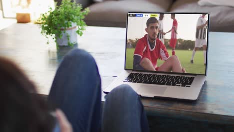 Biracial-couple-laptop-with-diverse-male-soccer-players-playing-match-on-screen