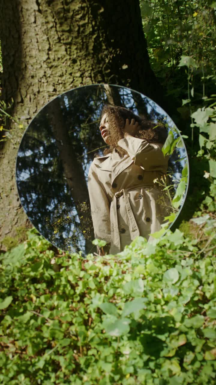 Woman reflected in a mirror in a forest