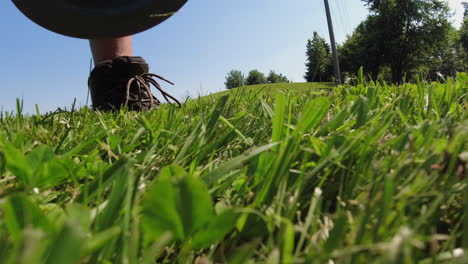 un primer plano de un hombre recogiendo un disco de la hierba durante un juego de disc golf, enfatizando la conexión entre el jugador y el equipo