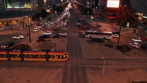 Forwards-fly-above-trams-driving-across-large-roundabout-and-busy-downtown-street.-Endless-queue-of-cars-stuck-in-evening-traffic-jam.-Warsaw,-Poland