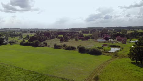 aerial footage over village space, beautiful green field, fresh grass and natural landscape, eastern poland, magical sky and high trees on horizontal