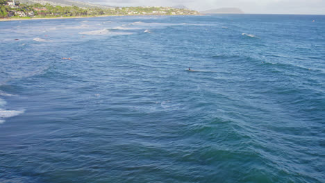 Practicantes-De-Kitesurf-Y-Surfistas-Salpican-La-Superficie-Del-Océano-Mientras-Esperan-La-Ola-Perfecta-Frente-A-La-Costa-De-Las-Islas-Hawaianas-De-Oahu