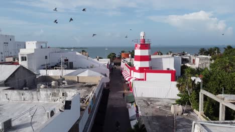 a drone shot of a beautiful white and red colored lighthouse at the shore of an ocean