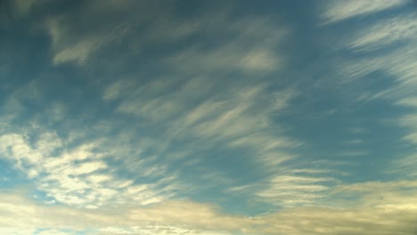 evening cirrus clouds move slowly across vibrant empty blue sky