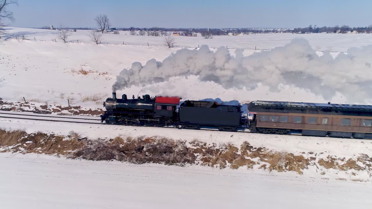 눈보라가 몰아친 후 객차를 끌고 연기와 증기를 내뿜는 골동품 증기 기관차의 공중 전망