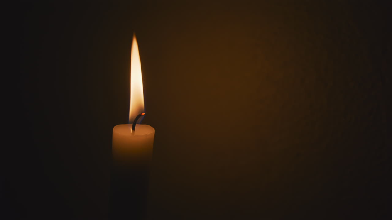 Close up of a stick candle burning on a black background