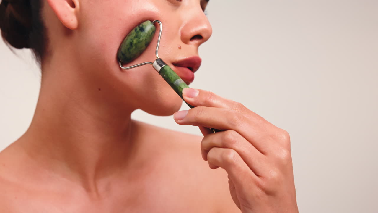 얼굴 마사지를 위해 재드 롤러를 사용하는 여성