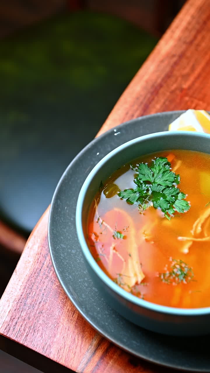 Skål med aromatisk hønsekødssuppe. Aromatisk hønsekødssuppe serveret med toast og en skive citron