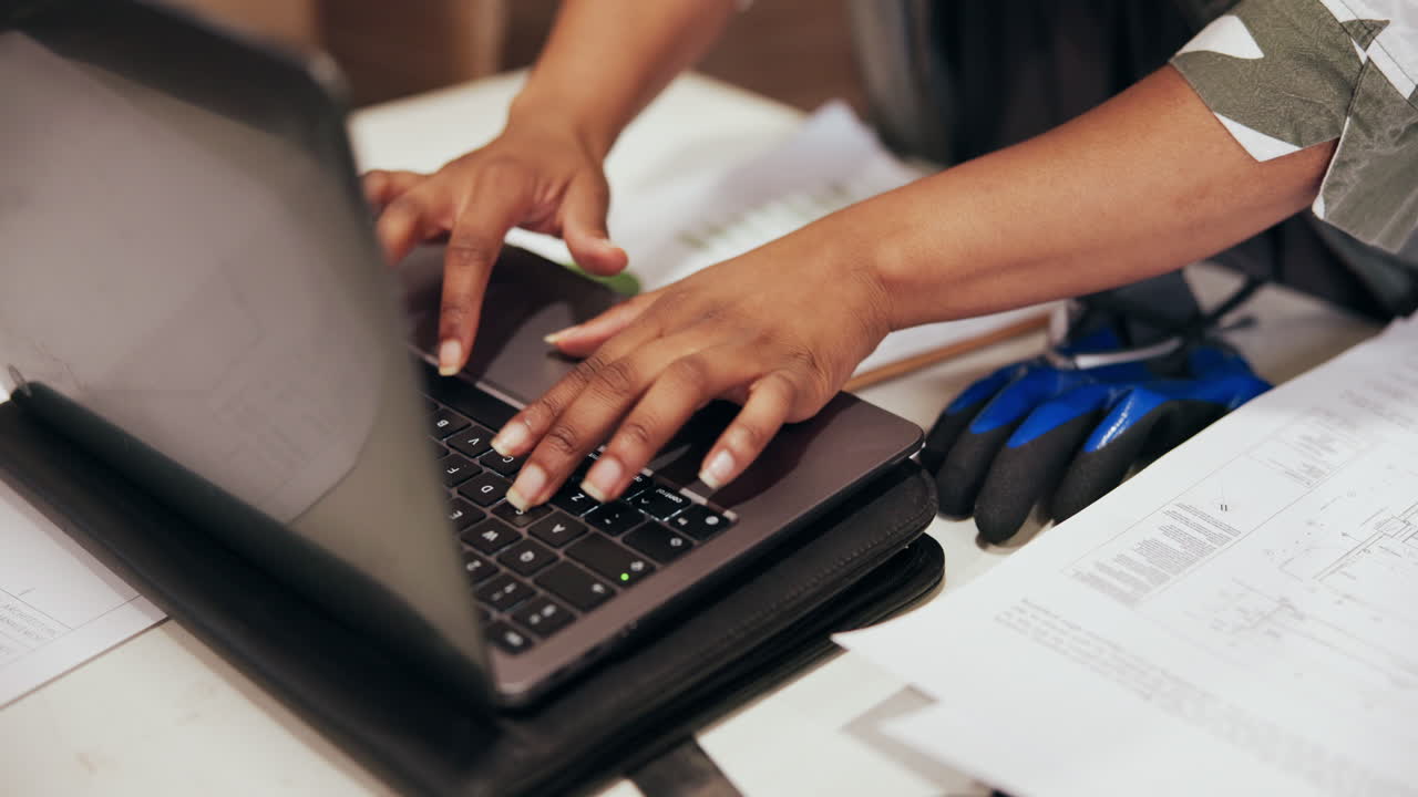 Close Up of Hands Typing on Laptop Keyboard with Documents