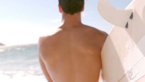 A-man-is-looking-at-the-sea-with-his-surfboard