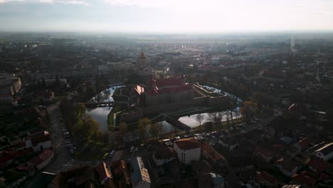 Panorama-aerial-drone-flight-over-castle-Cetatea-Făgărașului-in-Făgăraș,-România-during-sunset-in-autumn---Fagaras-in-Romania-is-a-touristic-city---water-reflection---bird-view