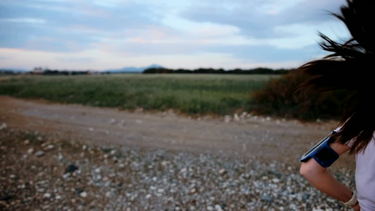 활발한 젊은 여성이 자연에서 조하고 음악을 듣고 있습니다.