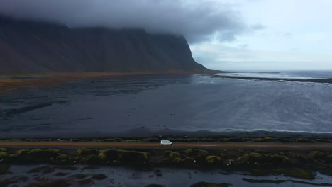 Viaje-Por-Carretera-En-Furgoneta-A-Lo-Largo-De-La-Carretera-Costera-Negra-En-La-Región-De-Stokksnes-Vestrahorn-Islandia,-Vista-Aérea-Amplia