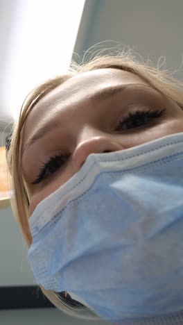a young woman with a pained expression looks directly at the camera, seated in a dental chair, highlighting her discomfort from a toothache. the scene captures the tension of waiting for dental treatment, emphasizing the importance of oral health and care