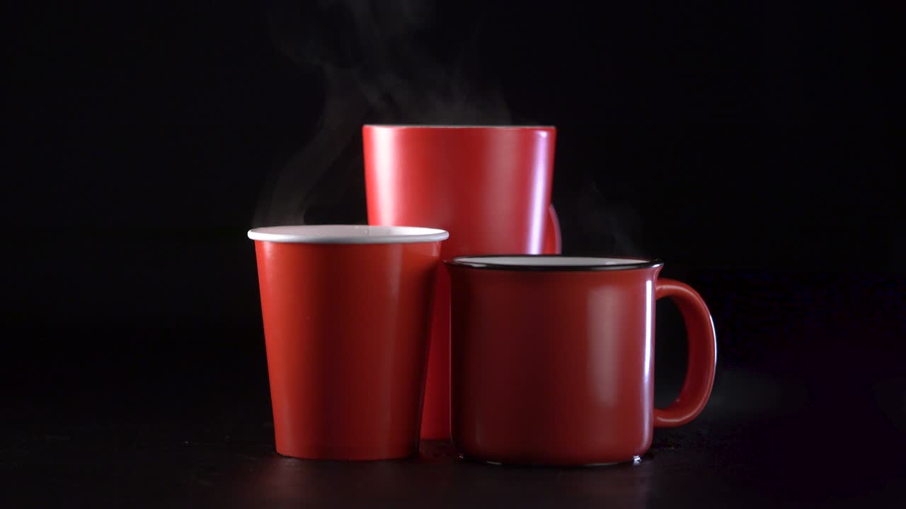 tres tazas de café rojas humeantes sobre un fondo negro