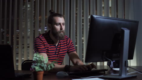bearded man working on computer at night