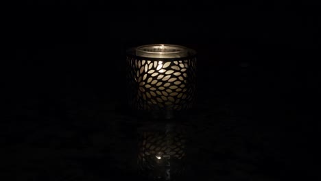 candle holder on table in dark lit with single flame flickering