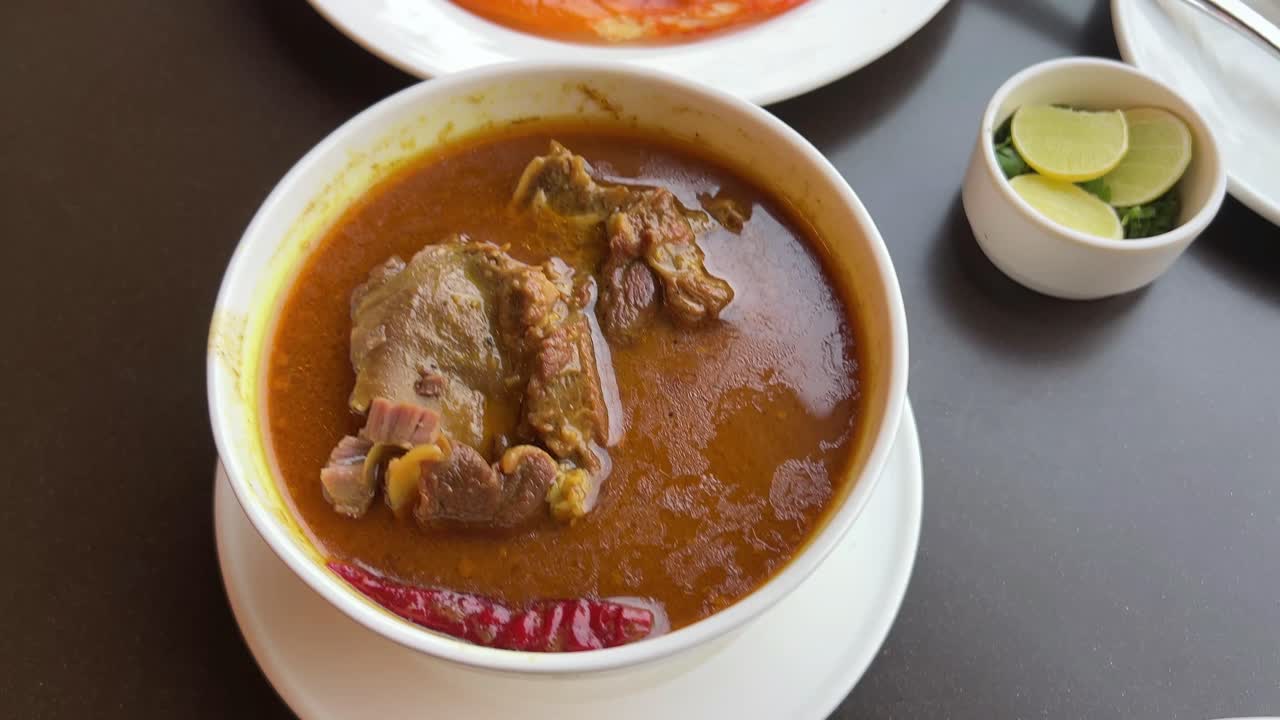 Assortment of chicken rogan josh with a oily orange lacha paratha looking delicious.