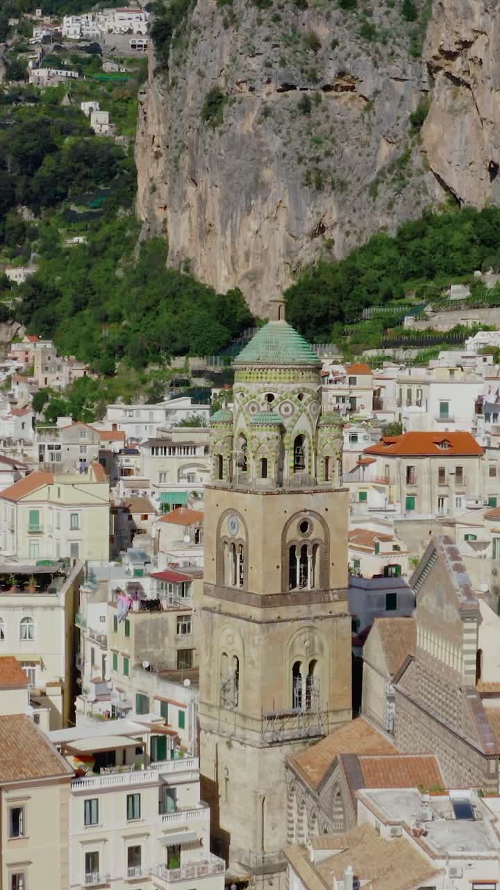 Video vertical de vuelo hacia el campanario de la catedral en la ciudad de Amalfi. Vista aérea de dron de la arquitectura italiana histórica en la Costa Amalfitana en un día soleado de verano.