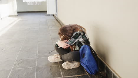 young girl sitting in school hallway with backpack, feeling overwhelmed and stressed, copy space