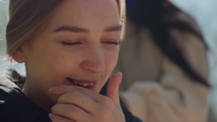 happy young woman resting outside with notes, smiling female enjoying peaceful moment amidst nature with notes, young lady displaying gentle smile as she reviews notes outdoors in soft sunlight
