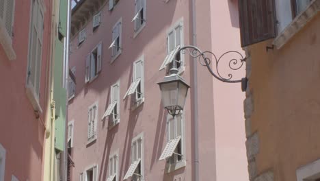 slowmotion shot of an old lantnern lamp in an alleyway in riva del garda with a rosa italian building in the background