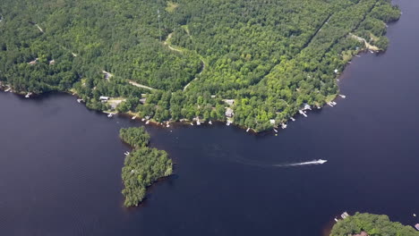 Boat-motors-away-as-aerial-tilts-toward-waterfront-homes-on-coast