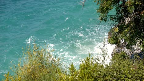 view beyond foamy waves crashing against the rocky shore of corfu island