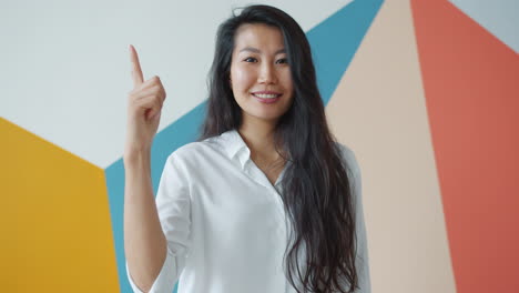 smiling asian woman pointing up