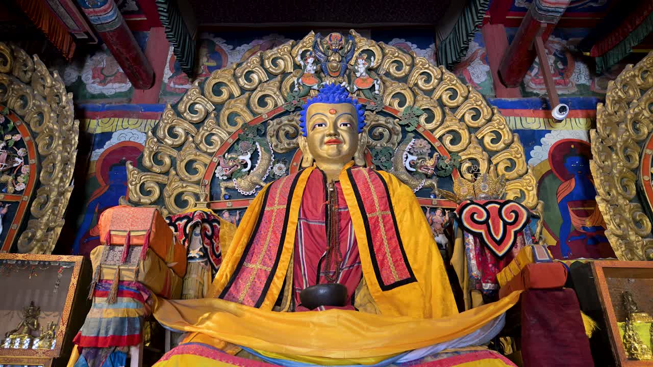 Close-up of a gilded Buddha statue face at Erdene Zuu Monastery, Mongolia. The historic deity features intricate gold details and vibrant blue hair, showcasing ancient religious artistry