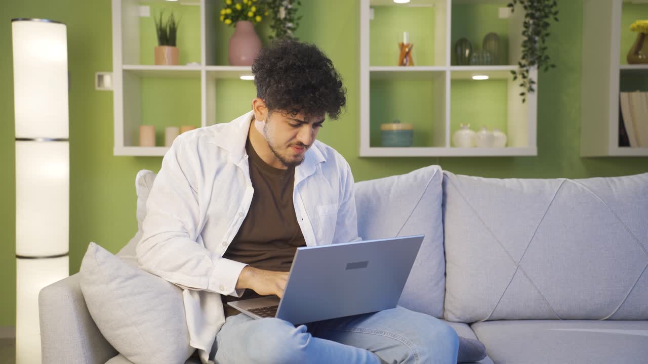 Bored and stressed young man at what he sees on laptop.