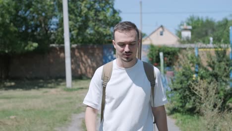 young man walking with guitar on street near forest