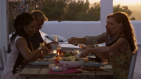 two couples eating dinner at a table on a rooftop terrace, shot on r3d