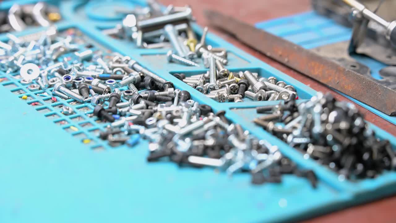 A close-up on the essential hardware—screws, nuts, and bolts—used in a Ukrainian workshop to assemble custom FPV drones for combat missions against Russia