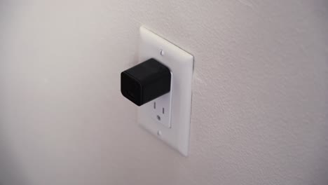 mujer conecta una cámara oculta que simula un cubo de cargador de teléfono celular negro