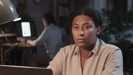 woman working on a laptop in a dimly lit office at night